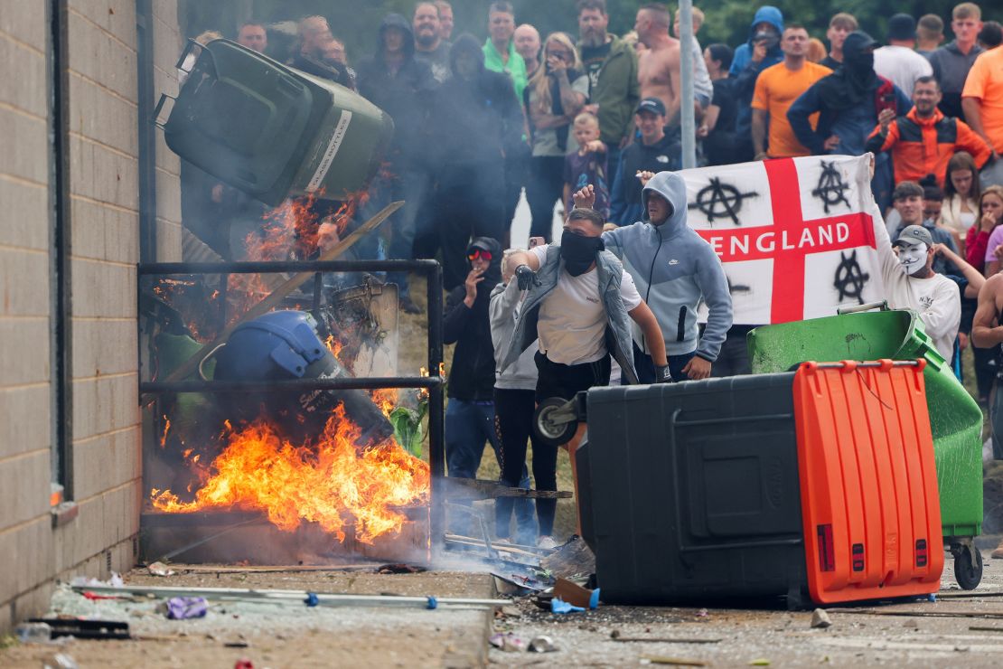 Protestors throw a blazing garbage bin outside the Holiday Inn Express in Rotherham on Sunday.