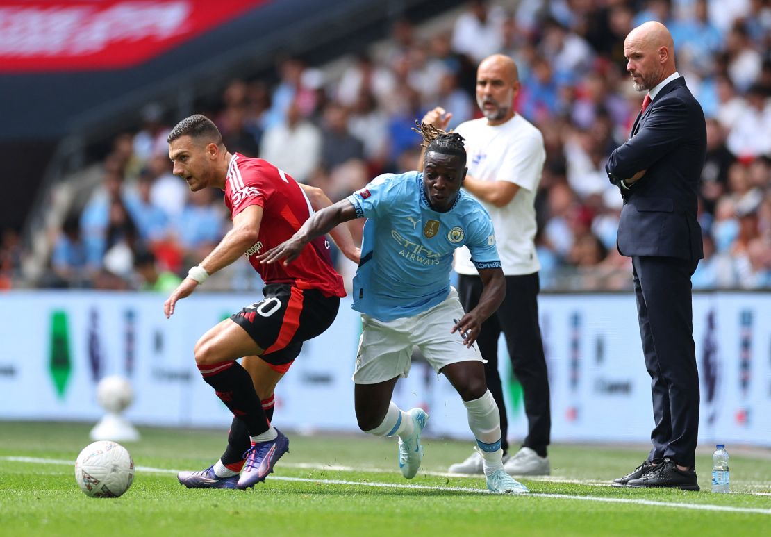 Soccer Football - Community Shield - Manchester United v Manchester City - Wembley Stadium, London, Britain - August 10, 2024 Manchester United's Diogo Dalot in action with Manchester City's Jeremy Doku as Manchester City manager Pep Guardiola and Manchester United manager Erik ten Hag look on REUTERS/Toby Melville