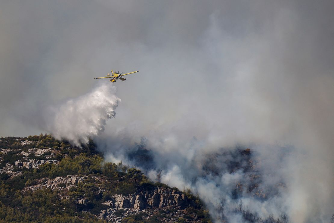 A firefighting plane pours water as a wildfire burns in Grammatiko, near Athens, August 12, 2024.