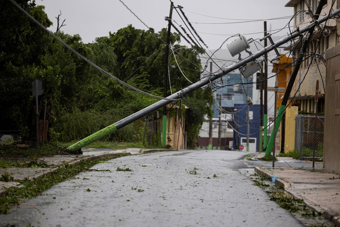 A power pole leans against a house in Fajardo, Puerto Rico, on Wednesday after Tropical Storm Ernesto.