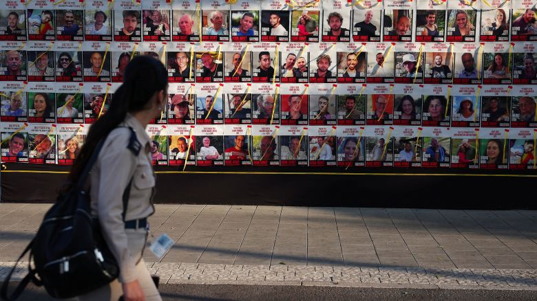 A woman walks next to a wall of posters of hostages kidnapped during the deadly October 7 attack on Israel by Hamas, amid the ongoing Israel-Hamas conflict, in Tel Aviv, Israel, August 21, 2024. REUTERS/Florion Goga