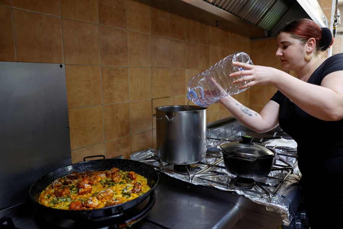 Oana Deacu uses bottled water to cook paella as the tap water has become undrinkable, in the town of Moraira, Alicante, Spain, on August 19.