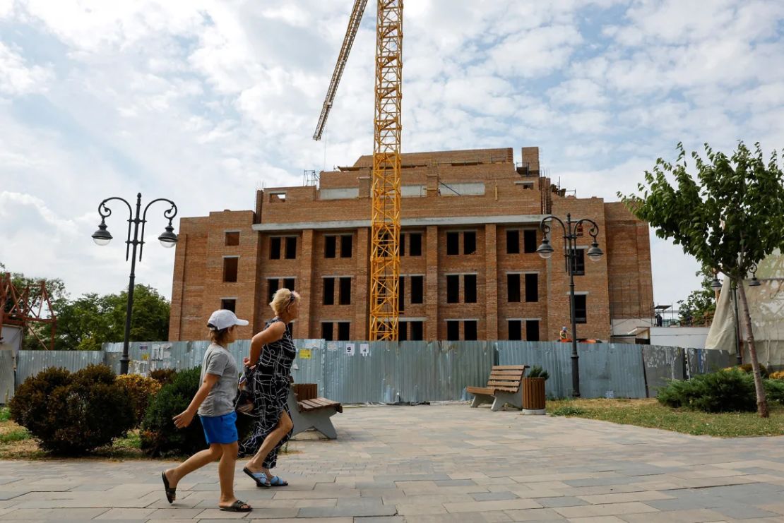 Un grupo de personas camina junto a las obras del Teatro Dramático de Mariúpol el 28 de agosto de 2024.