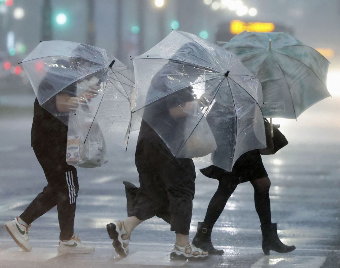 Pedestrians with umbrellas battle the strong winds and heavy rains caused by Typhoon Shanshan in Kagoshima on August 28, 2024.