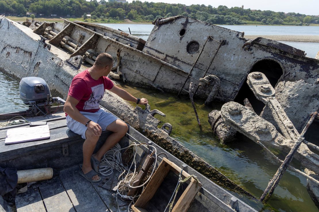 A fisherman looks at a sunken warship.