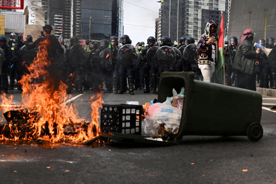 Fire burns ahead of a Victoria Police riot squad line during a rally against the Land Forces International Land Defense Exposition in Melbourne, Australia September 11, 2024.