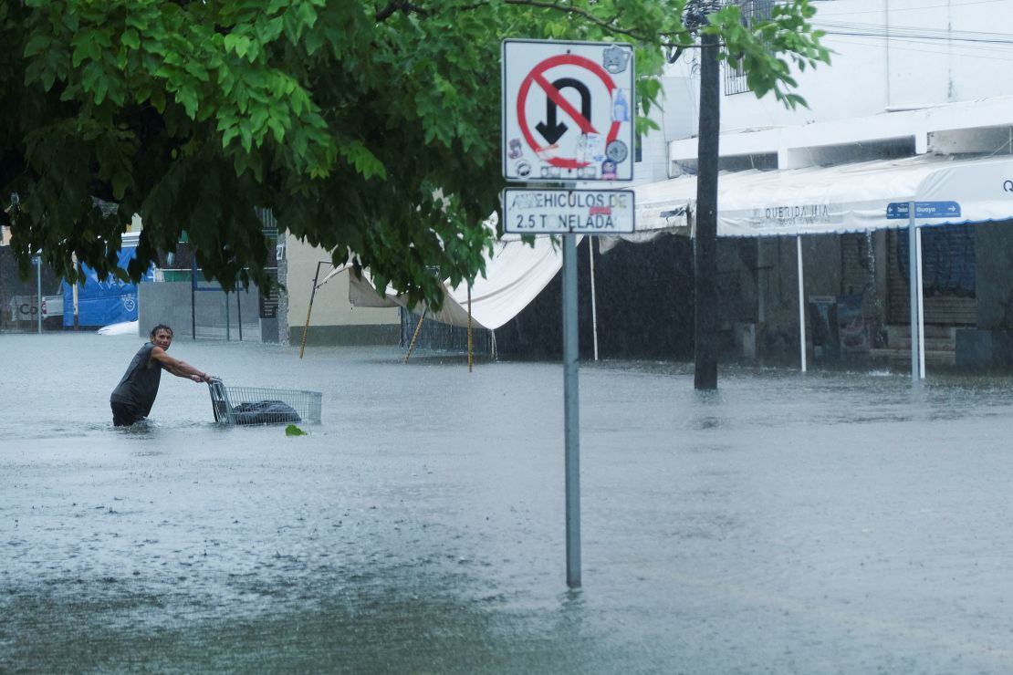 A man pushes a cart on a flooded street during rainfall caused by Helene, in Cancun, Mexico, September 25, 2024.