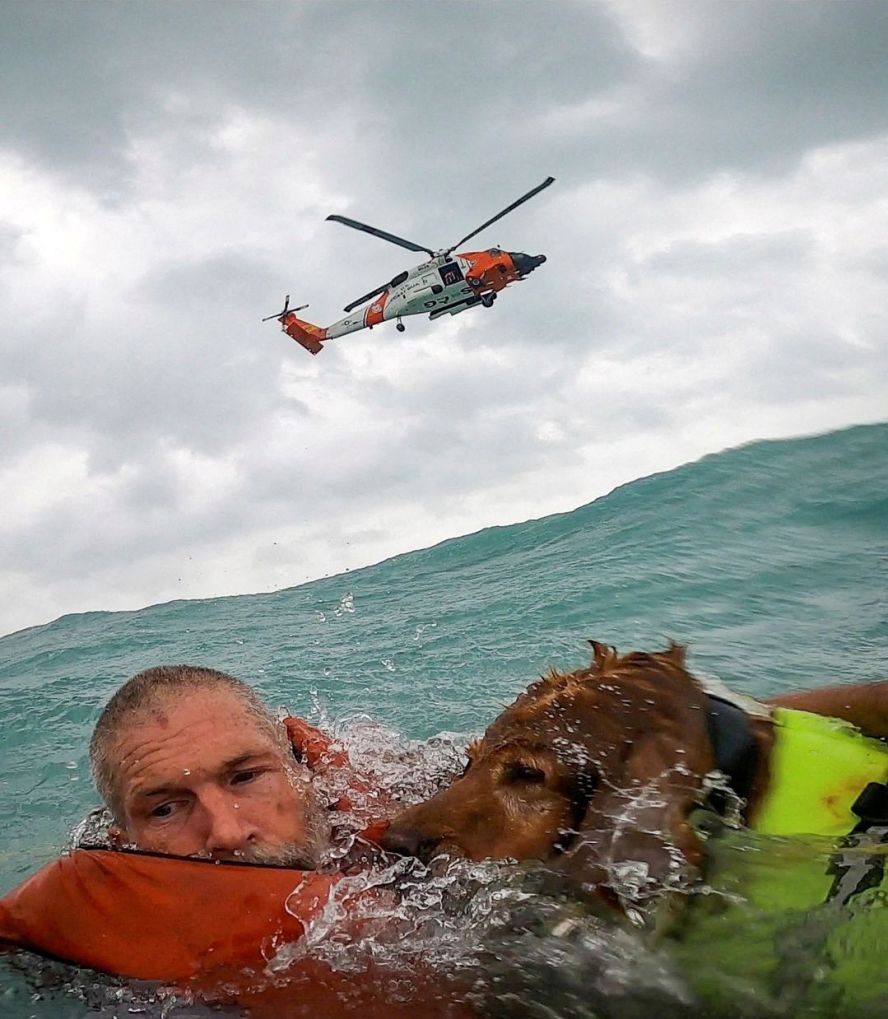 In this screengrab taken from a <a  target="_blank">United States Coast Guard body cam</a>, a man and his dog are seen being rescued after his sailboat became disabled and started taking on water off Sanibel Island, Florida, on September 26.