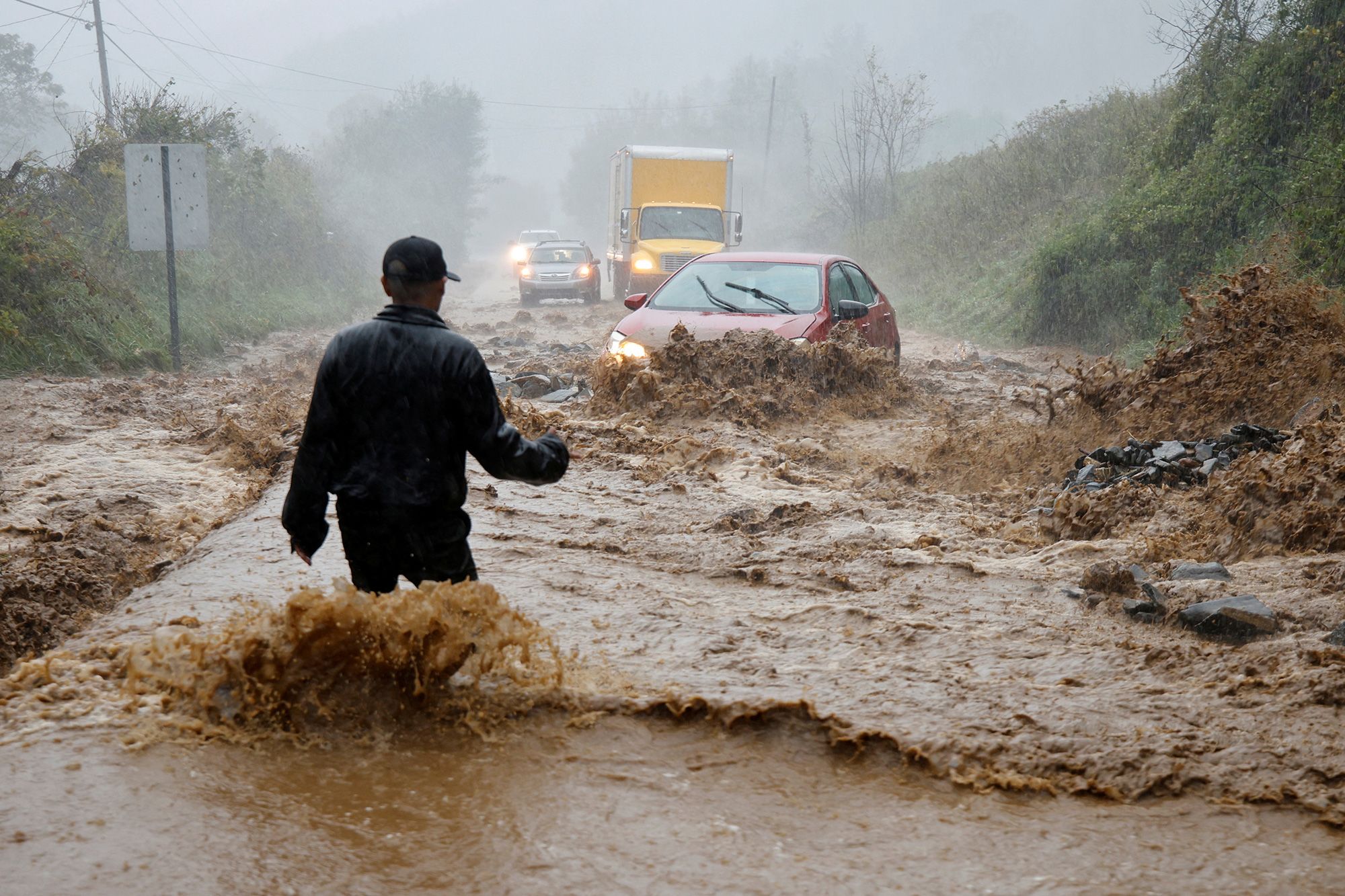 A person assisting a stranded driver in Boone, North Carolina, after heavy rains.