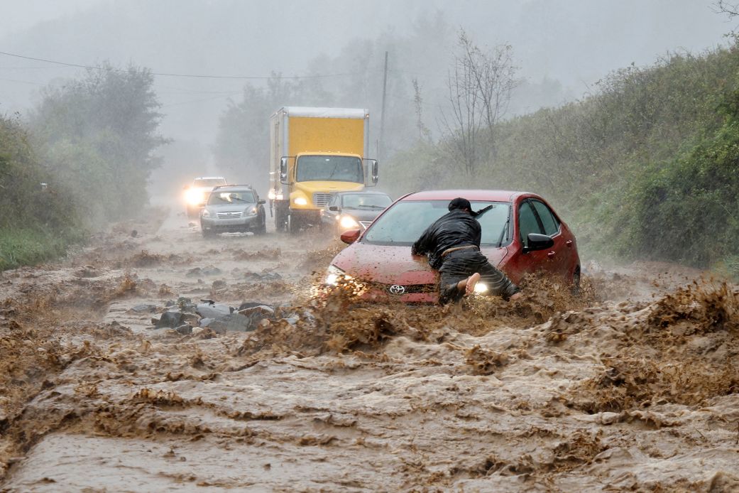 A resident helps free a car that became stranded in a stretch of flooding road on the outskirts of Boone, North Carolina, on September 27, 2024, during Hurricane Helene.
