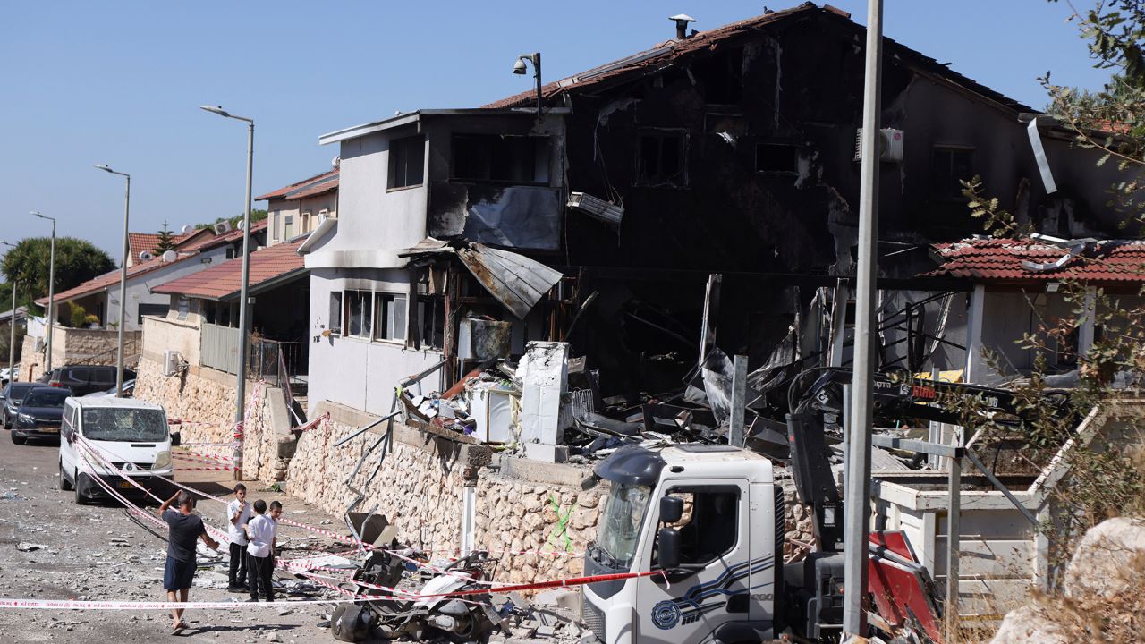 People stand next to a house damaged by a rocket attack from Lebanon on September 28, in Safed, Israel.