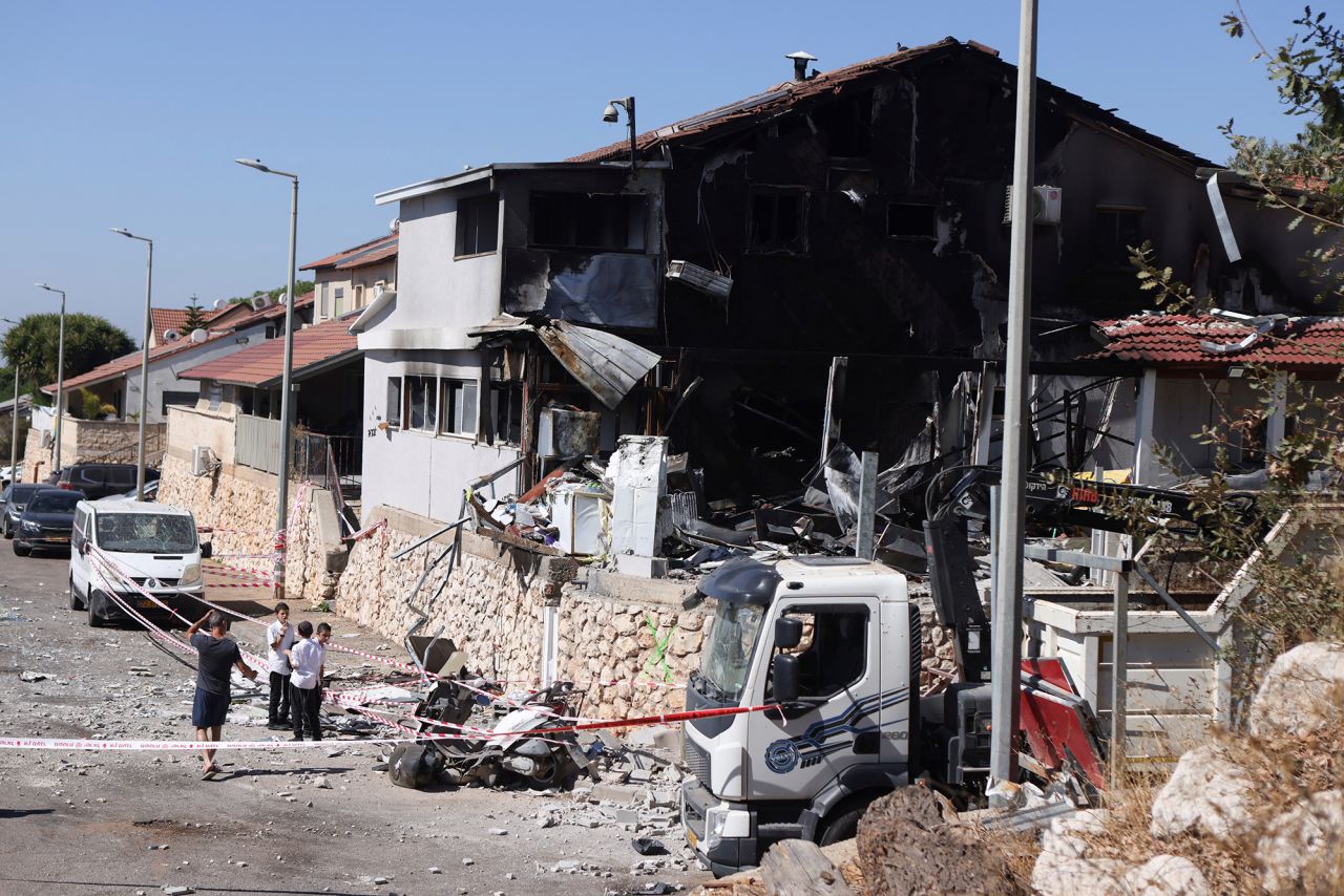 People stand next to a house damaged by a rocket attack from Lebanon on September 28, in Safed, Israel.