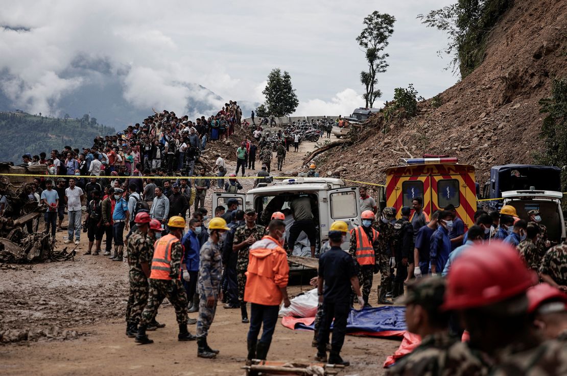 People stranded at the Tribhuwan Highway gather as rescue personnel put the bodies retrieved from the landslide triggered by heavy rainfall into an ambulance in Dhading, Nepal, September 29, 2024.