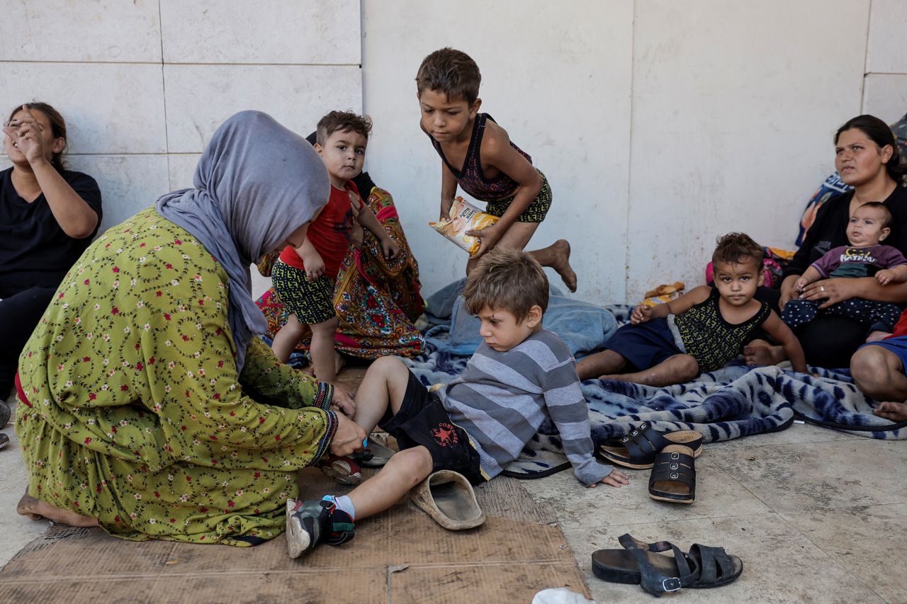 Displaced from Dahiyeh, southern Beirut suburb, Asmaa Kenji, mother of three, helps her son put on his shoes, as they live on the streets of central Beirut after fleeing Israeli air strikes, on September 29.