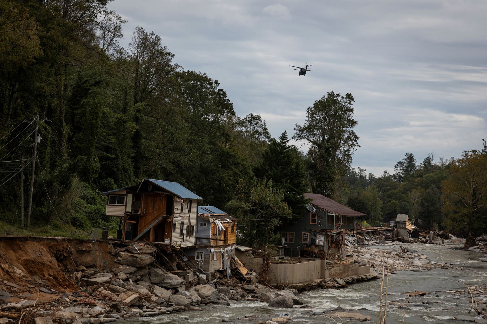 A helicopter flies near damaged buildings in Bat Cave on Monday.