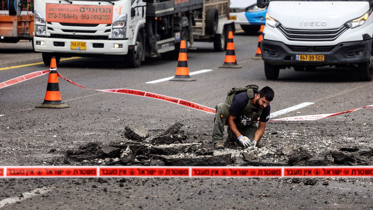 A security official handles the remains of a rocket that landed on a highway after it was fired from Lebanon into Israel, near Kfar Qasim, on October 1.