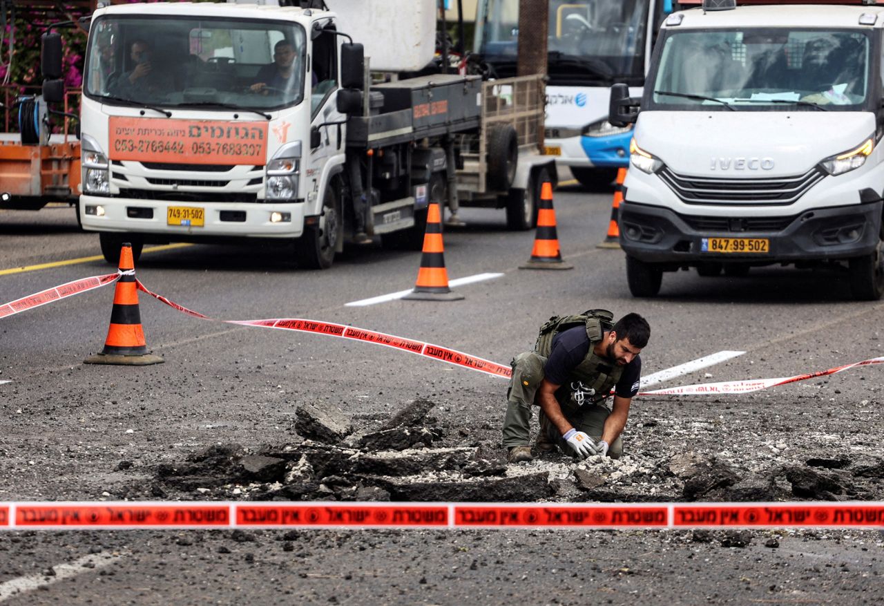 A security official handles the remains of a rocket that landed on a highway after it was fired from Lebanon into Israel, near Kfar Qasim, on October 1.