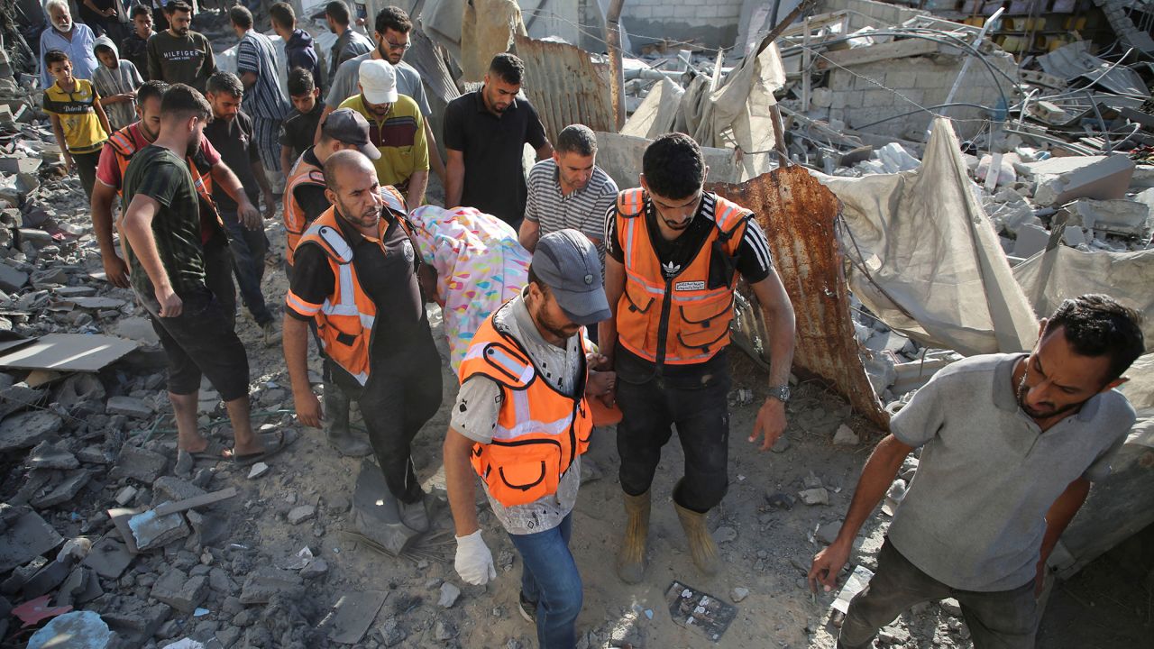 Palestinians carry the body of a woman casualty at the site of Israeli strikes in Khan Younis, Gaza, on October 2.