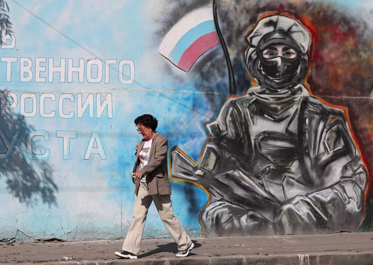 A woman walks past a mural depicting a soldier with the Russian flag in Simferopol, Crimea, on October 2, 2024.