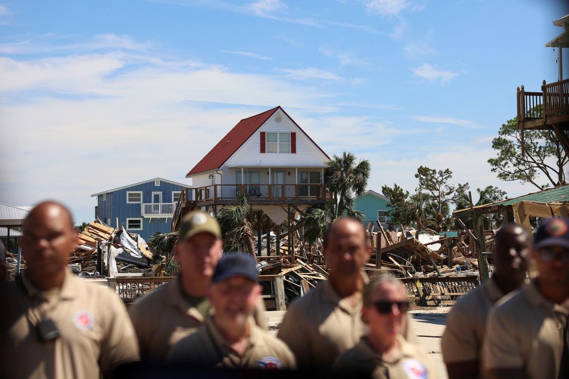 First responders watch President Joe Biden's motorcade against a backdrop of damaged property in Keaton Beach, Florida, on Thursday.