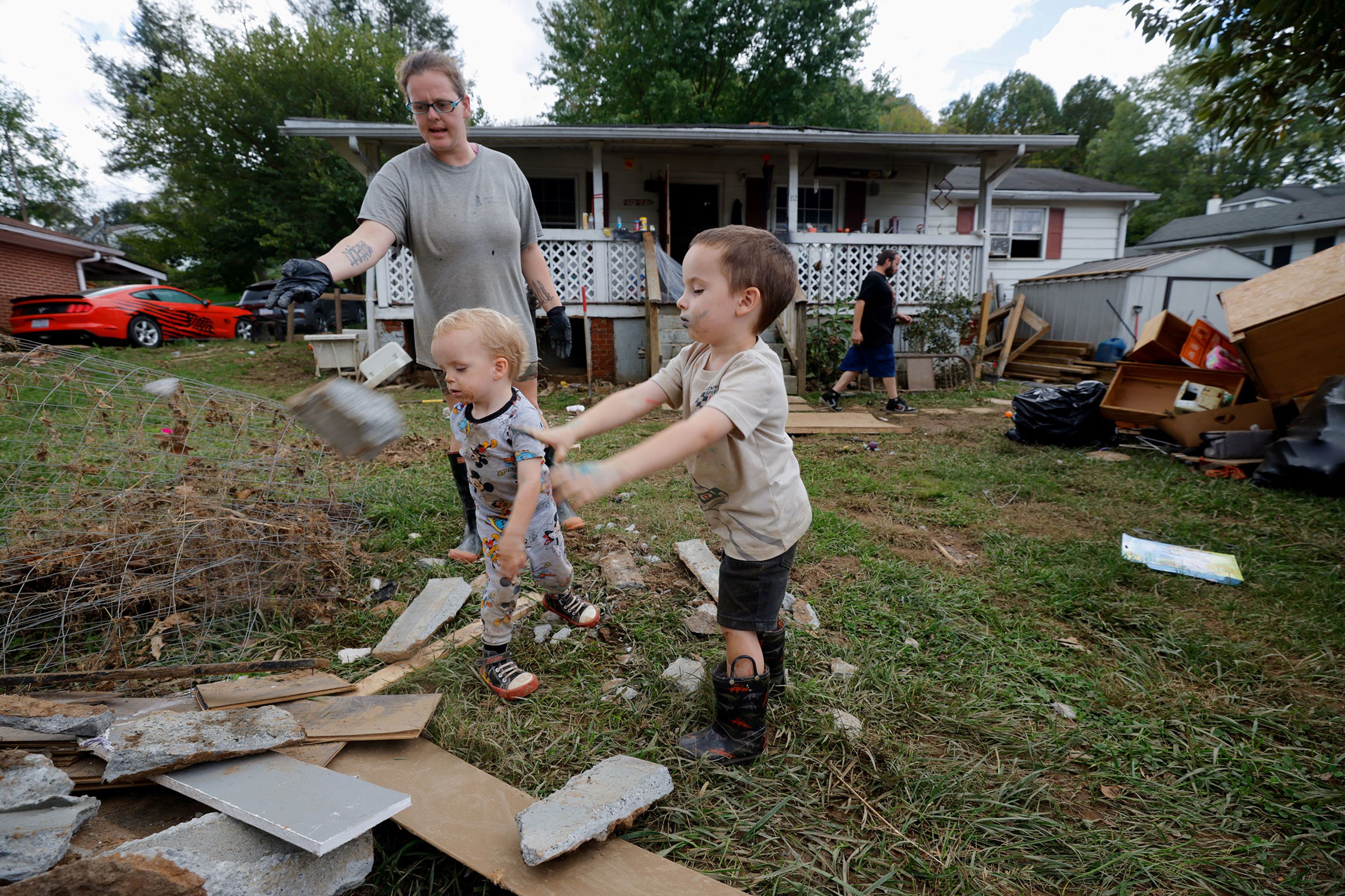 Martika Stansell and two of her children help pile debris in front of their flooded house in Canton, North Carolina, on Thursday, October 3.