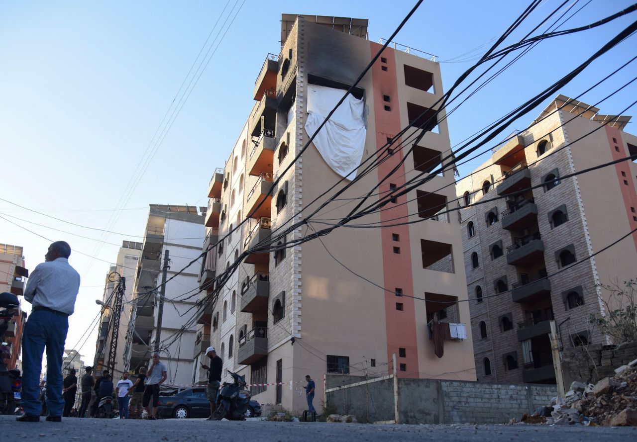 People stand at the site hit by an Israeli strike that killed Saeed Atallah Ali in Tripoli, Lebanon, on Saturday.