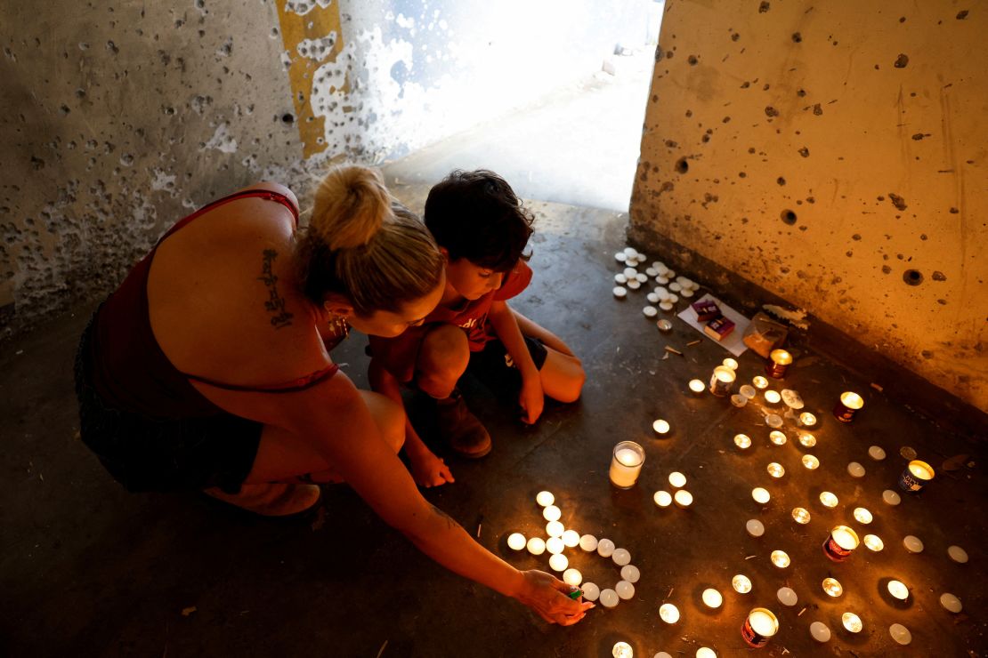 A boy and his mother light memorial candles at a bomb shelter where people were killed during Hamas' deadly October 7 attack on October 7, 2024, near Kibbutz Mefalsim in southern Israel. This is the first anniversary since the attack.