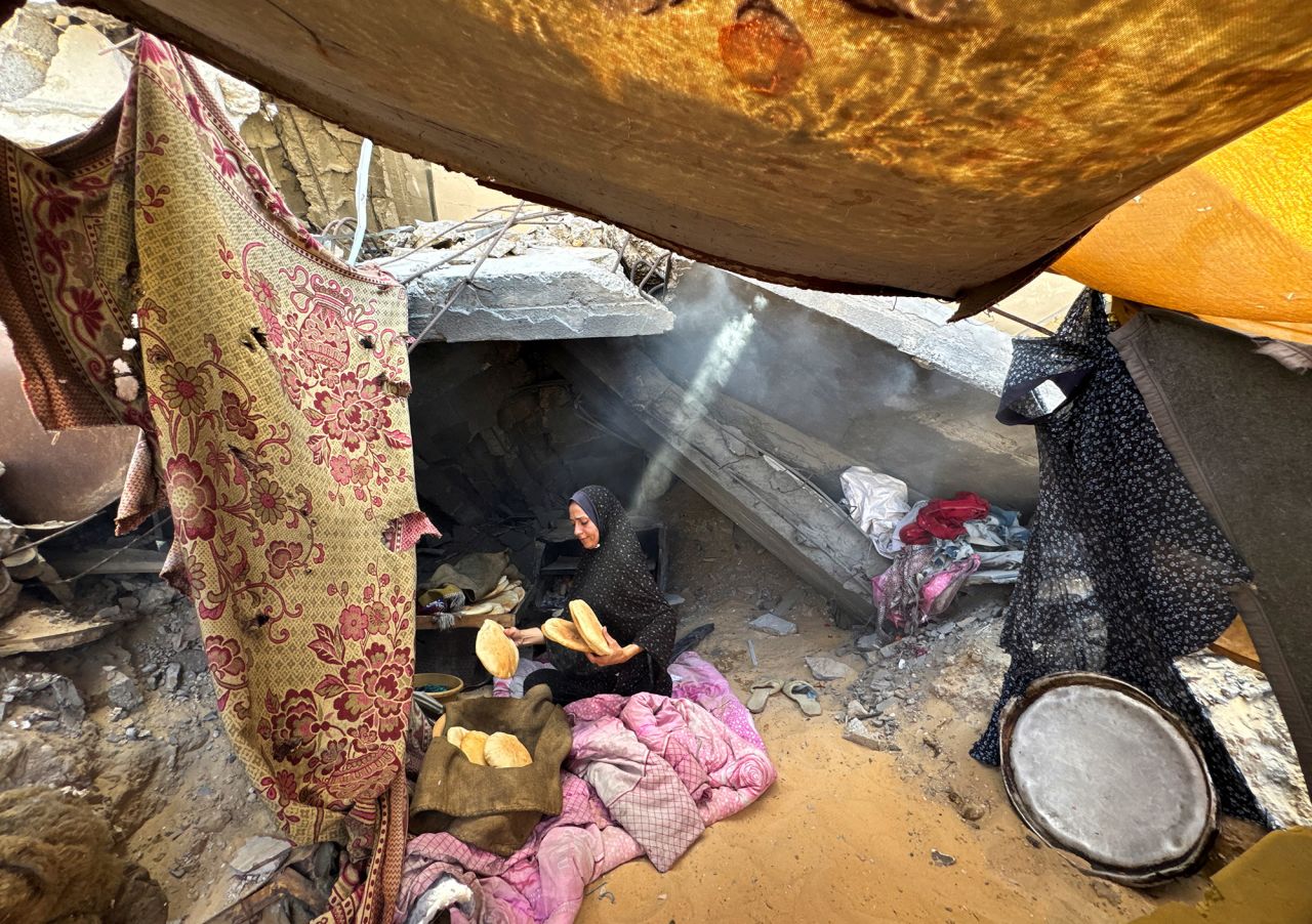 A Palestinian woman holds pita bread in a makeshift tent next to rubble of a house destroyed, in Khan Younis, southern Gaza, on Monday.