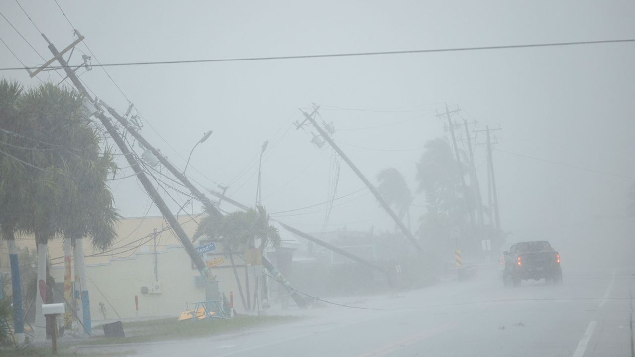 A motorist drives past broken utility poles downed by strong wind gusts as Hurricane Milton approaches Fort Myers, Florida, on Wednesday.