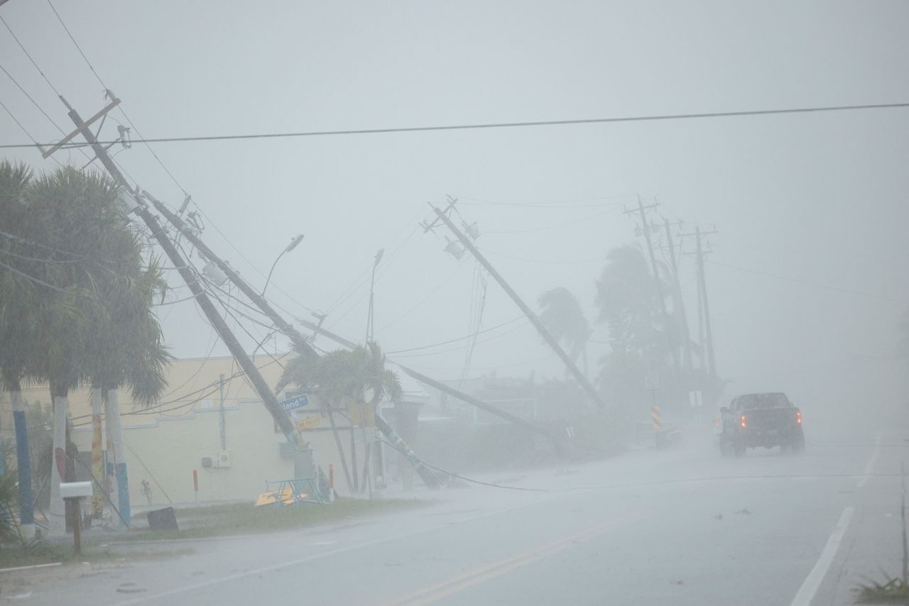 A motorist drives past broken utility poles downed by strong wind gusts as Hurricane Milton approaches Fort Myers, Florida, on Wednesday.