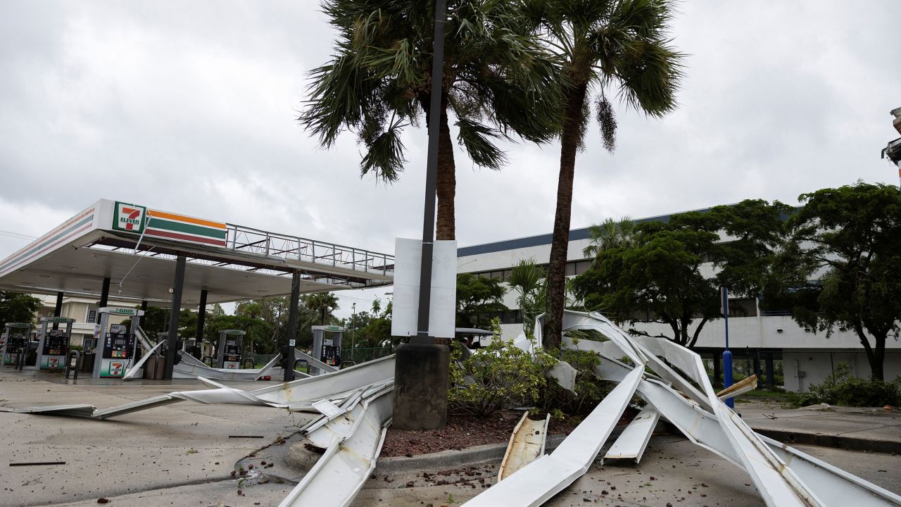 Parts of the roof of a gas station lie around palm trees on Wednesday in Fort Myers.