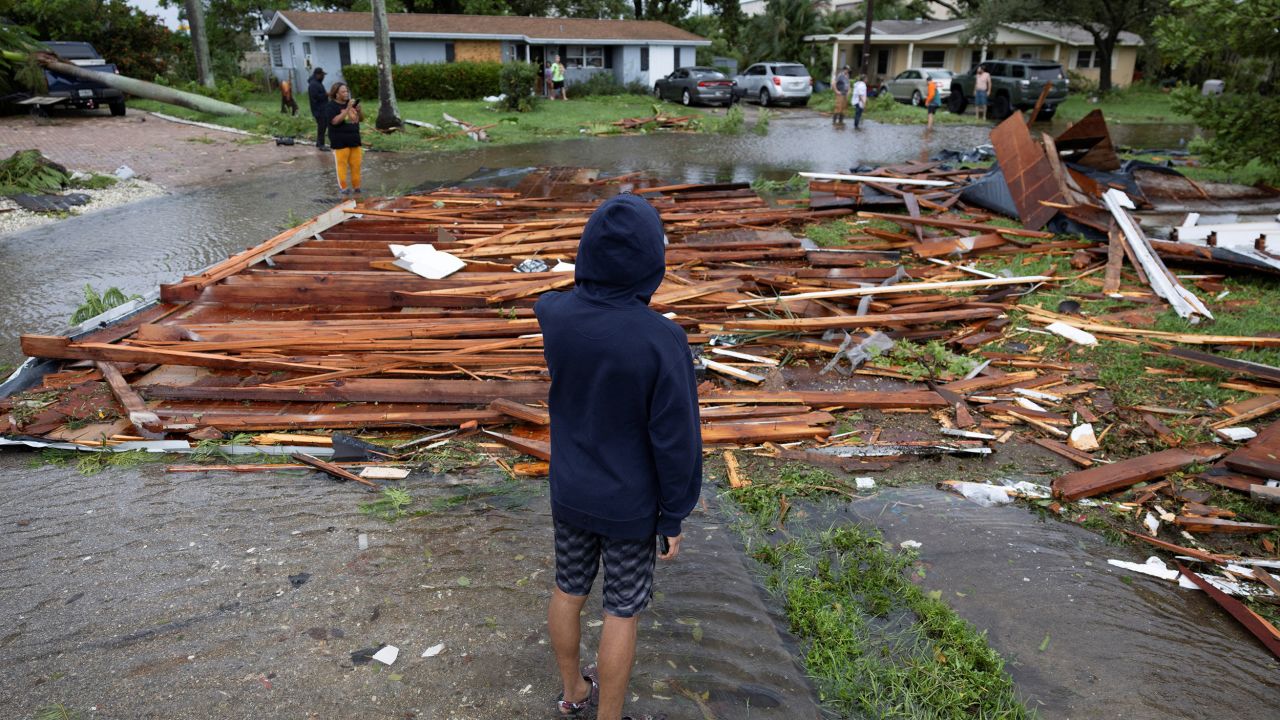 A man looks at a roof on a street from a nearby house after a likely tornado hit the area in Fort Myers, Florida, on Wednesday.