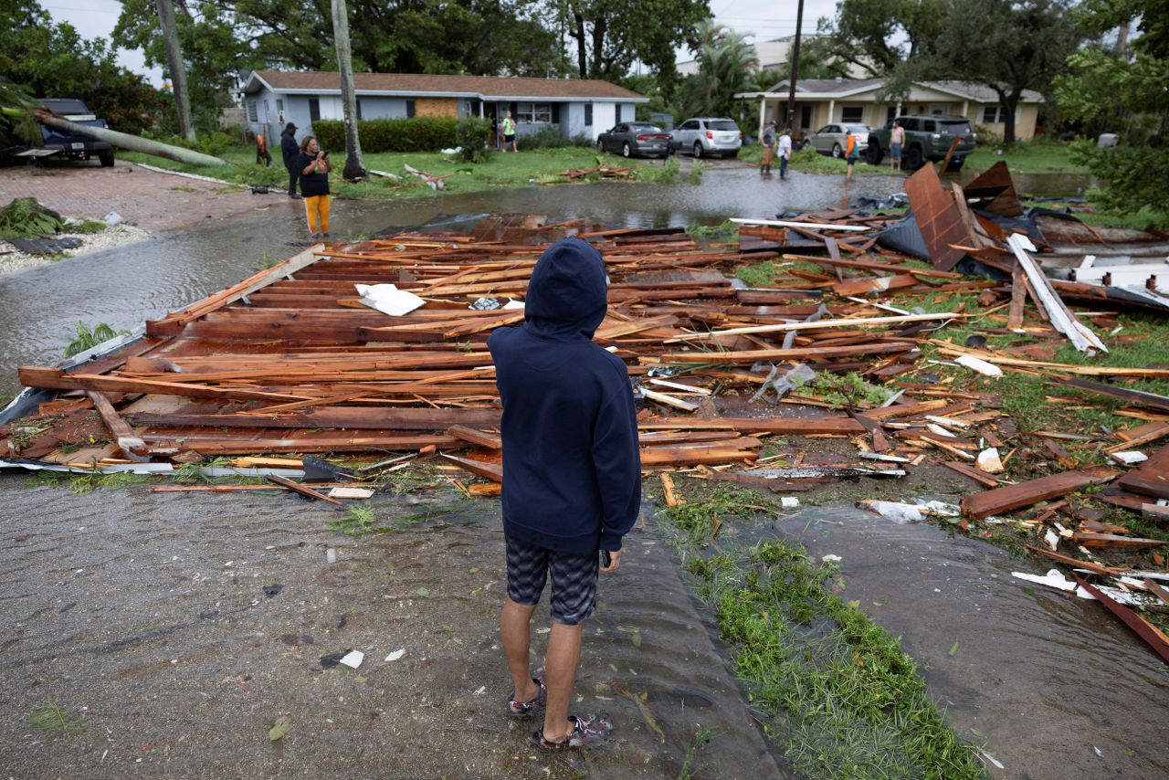 A man looks at a roof on a street from a nearby house after a likely tornado hit the area in Fort Myers, Florida, on Wednesday.