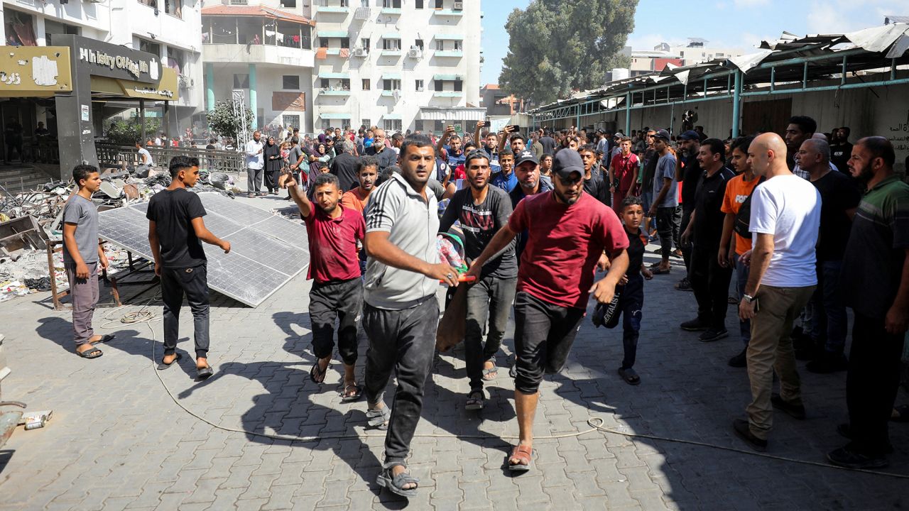 Palestinians carry a casualty in the aftermath of an Israeli strike at al-Remal clinic, which had been sheltering displaced people in Gaza City, on October 10.