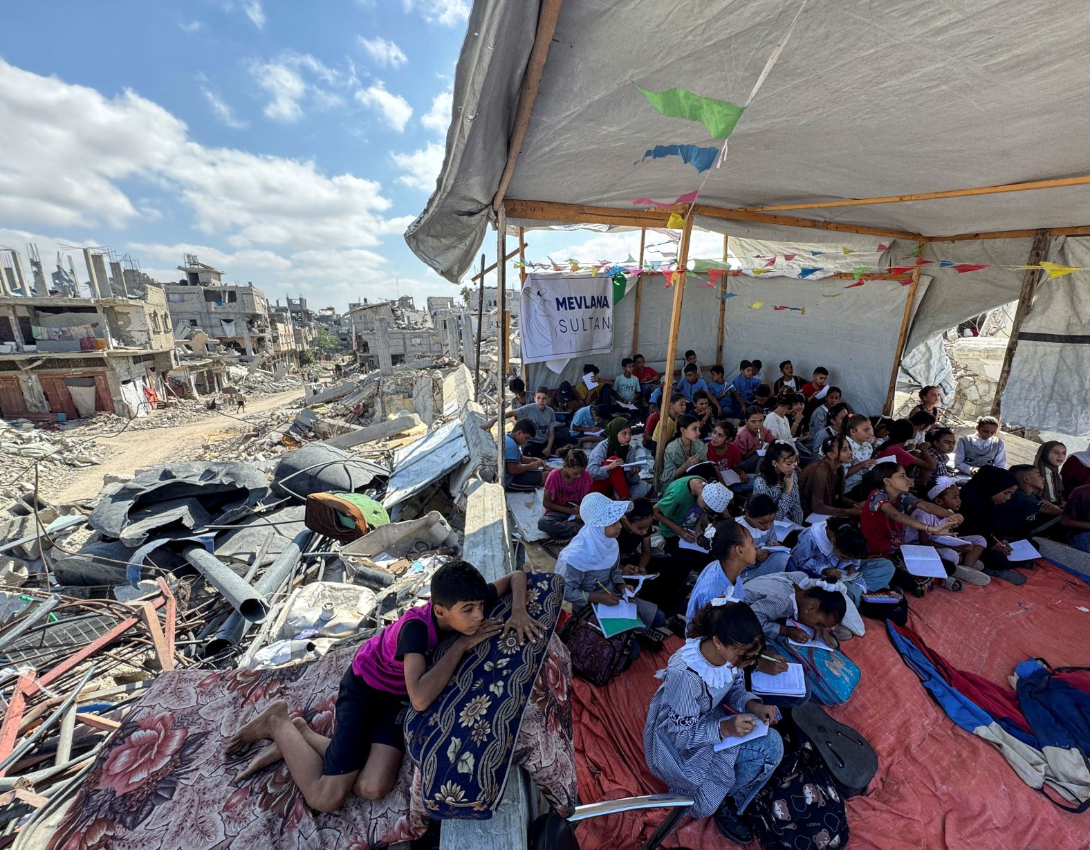 Palestinian students in Khan Younis, Gaza, attend a class in a tent set up on the ruins of the house of teacher Israa Abu Mustafa on Thursday, October 10.