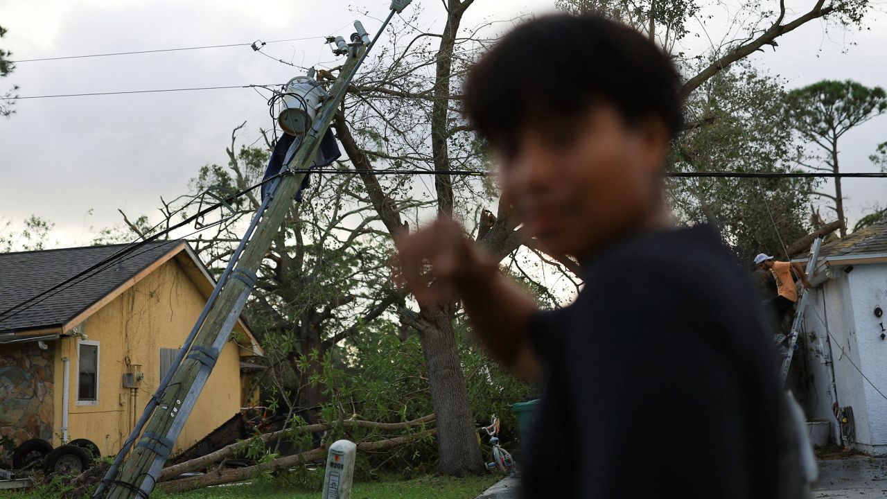 A person looks on, with a fallen tree and damaged utility pole in the background, near Fort Pierce in St. Lucie County, Florida, on October 10, 2024.