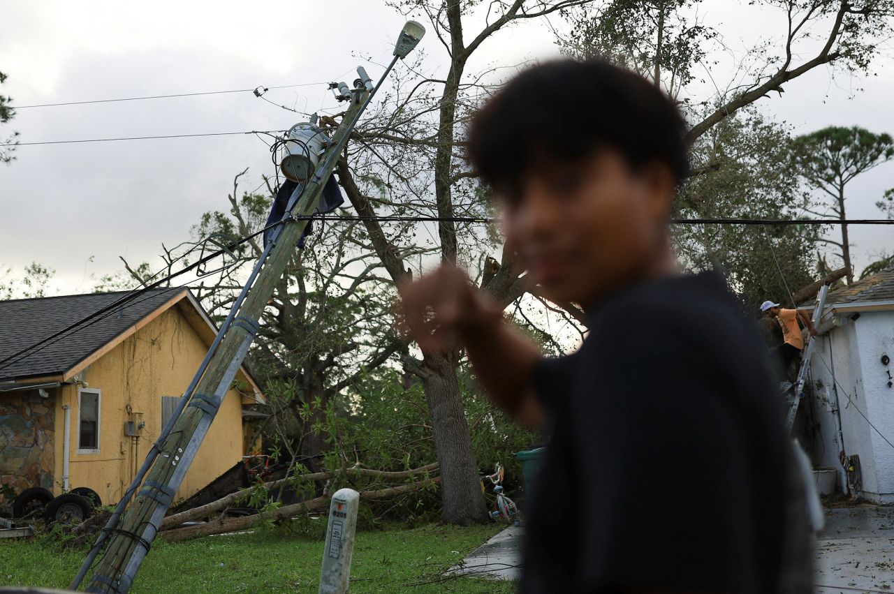 A person looks on, with a fallen tree and damaged utility pole in the background, near Fort Pierce in St. Lucie County, Florida, on October 10, 2024.