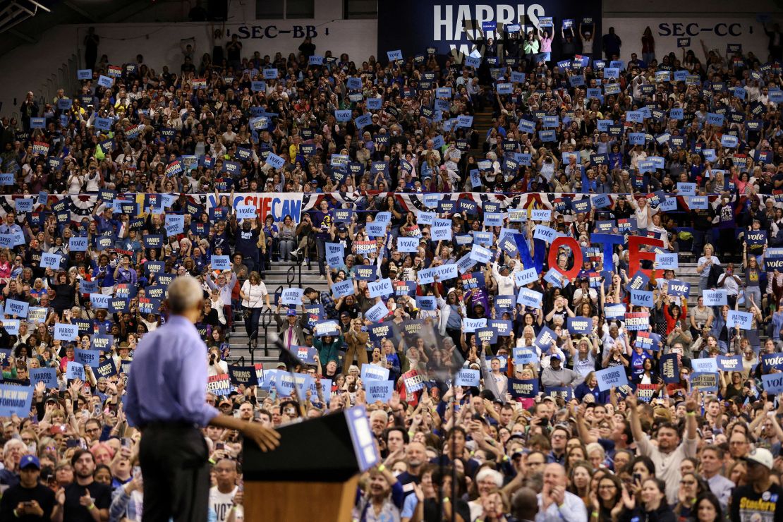 People hold signs as former President Barack Obama speaks during a campaign event in support of Vice President Kamala Harris in Pittsburgh on October 10, 2024.