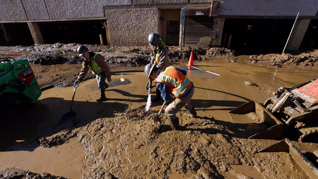 Workers from Alabama with an emergency management and disaster recovery company work to clear mud from the streets of the city's Biltmore Village district two weeks after Hurricane Helene, in Asheville, North Carolina, on October 11.