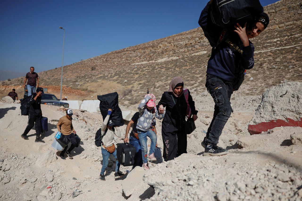 People carry their belongings while crossing from Lebanon into Syria on October 14.