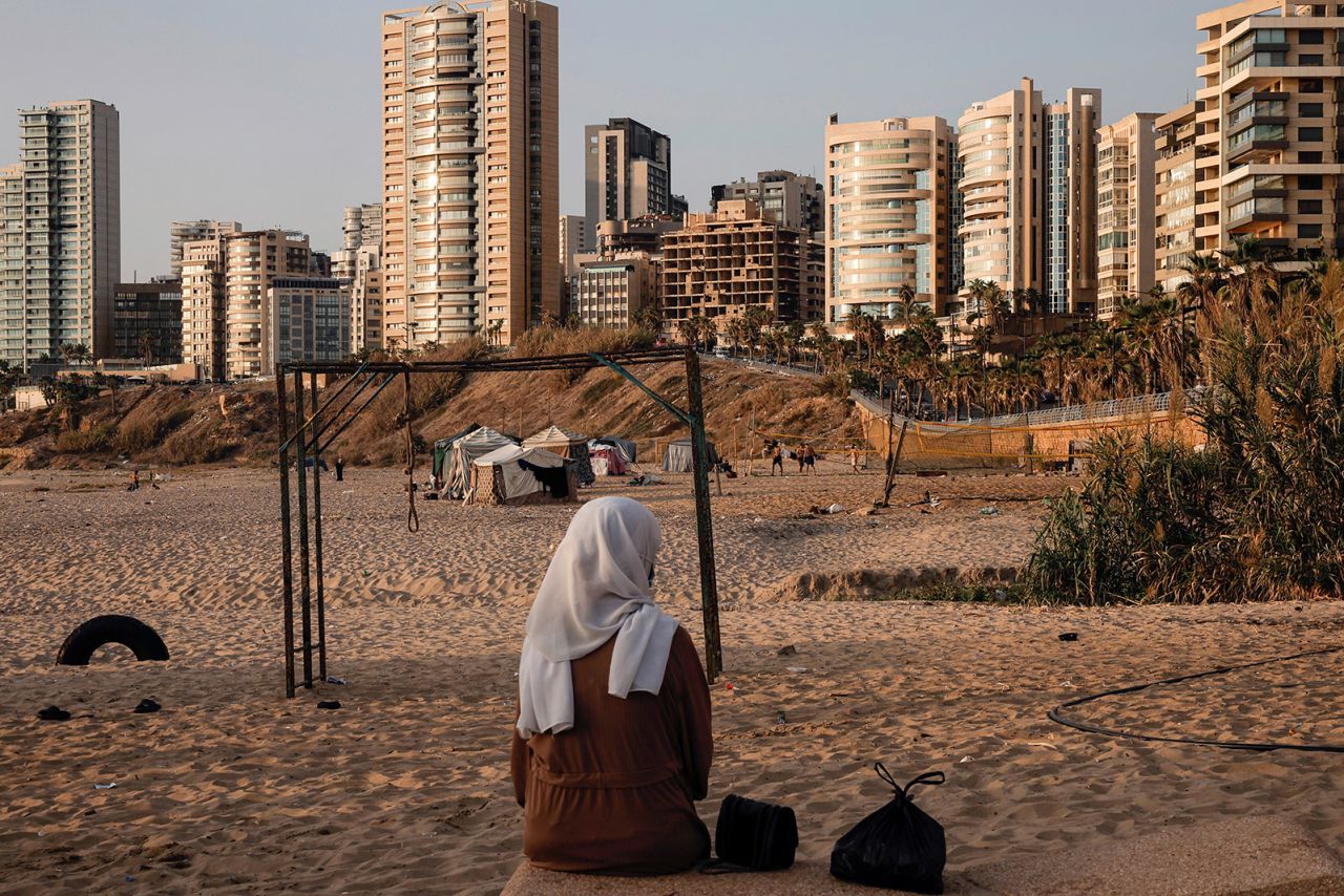 A displaced young woman sits by makeshift shelters on a beach in Beirut, Lebanon, on October 16, 2024. More than a million people have been displaced amid hostilities between Hezbollah and Israeli forces, according to UNICEF.