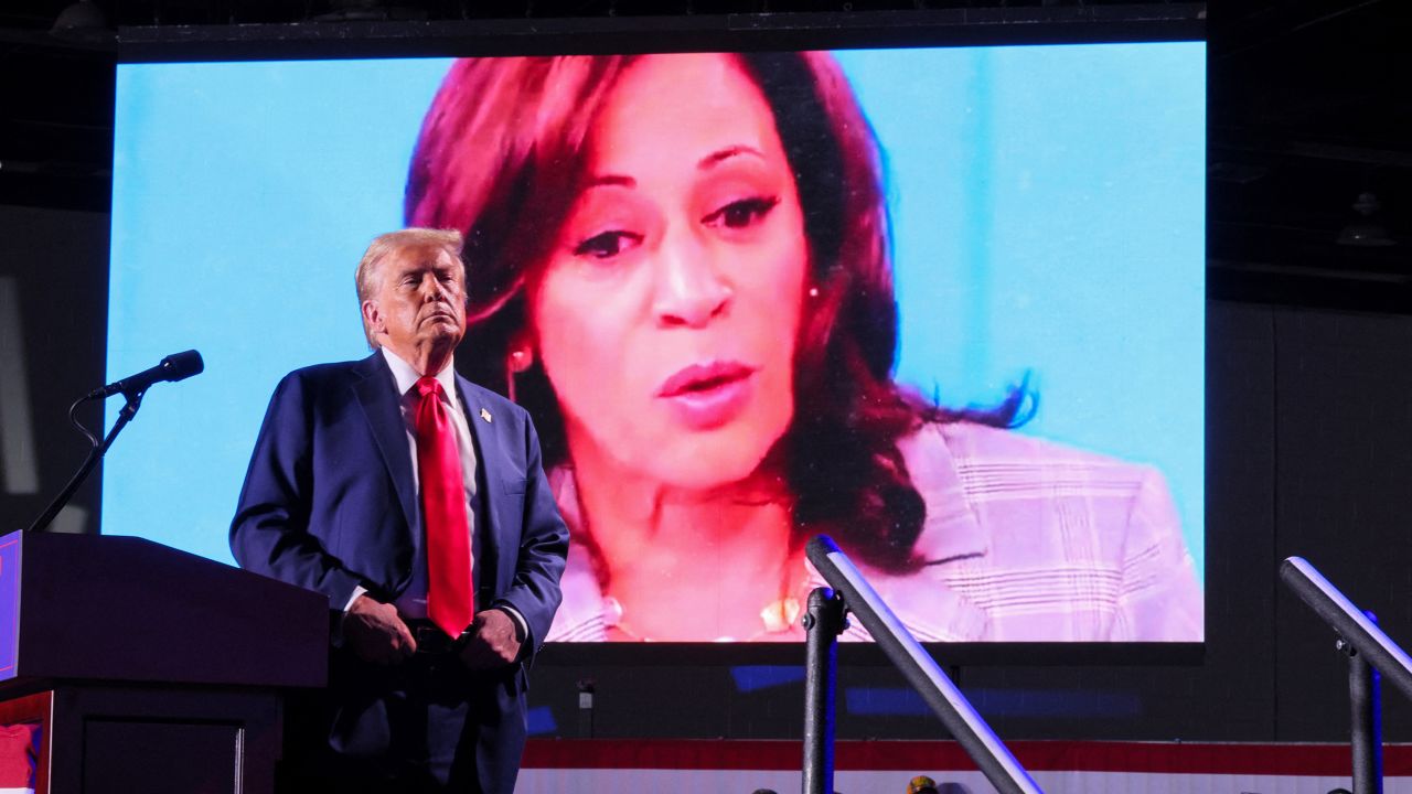 Republican presidential nominee and former U.S. President Donald Trump looks on as Democratic presidential nominee and U.S. Vice President Kamala Harris' face appears as a video plays on a screen, during a rally at Huntington Place in Detroit, Michigan, U.S. October 18, 2024. REUTERS/Brian Snyder