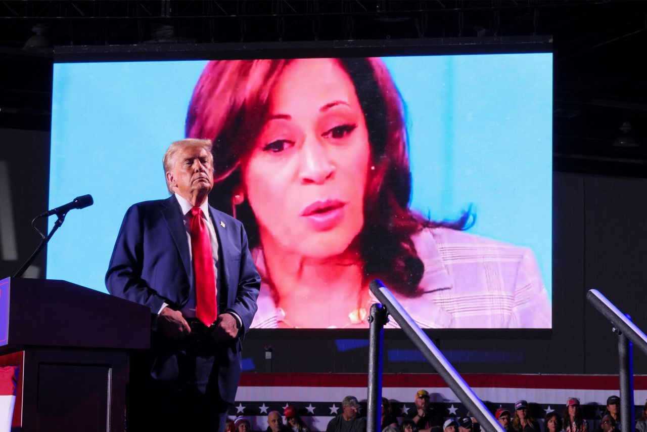 Republican presidential nominee and former U.S. President Donald Trump looks on as Democratic presidential nominee and U.S. Vice President Kamala Harris' face appears as a video plays on a screen, during a rally at Huntington Place in Detroit, Michigan, U.S. October 18, 2024. REUTERS/Brian Snyder