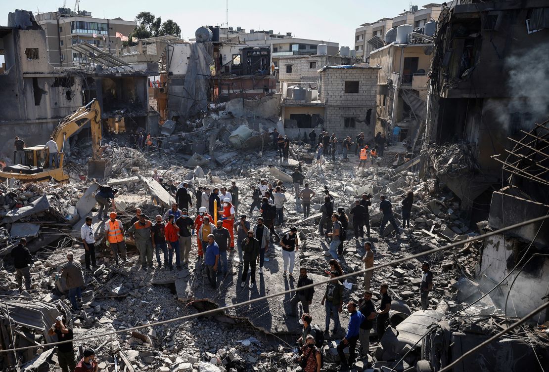 Emergency workers and locals stand at the site of a demolished building after an Israeli strike near the Rafik Hariri University Hospital in Beirut, Lebanon, on October 22, 2024.