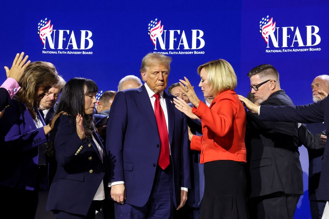 People stretch their hands towards former President Donald Trump as they pray at the national Faith Advisory Summit in Powder Springs, georgia, on October 28, 2024.