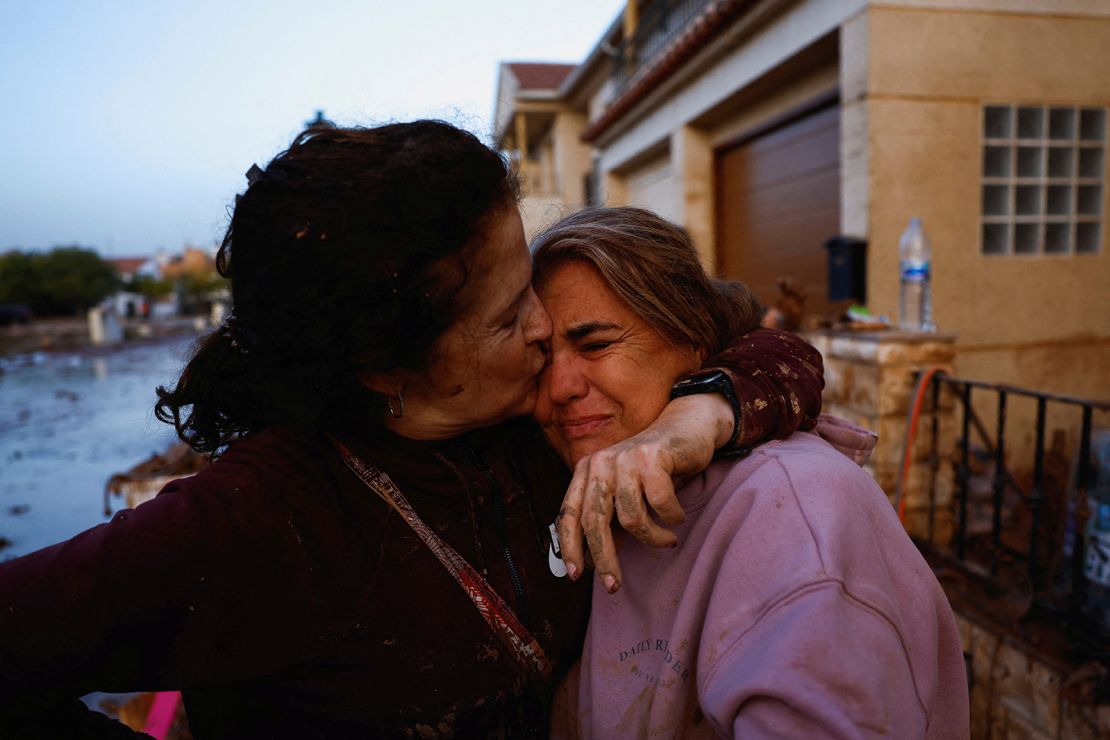 Eva Defez, 50, gets hugged by a friend outside her home after spending the night stranded at her home with her family due to floods in Utiel, Spain, October 30, 2024.