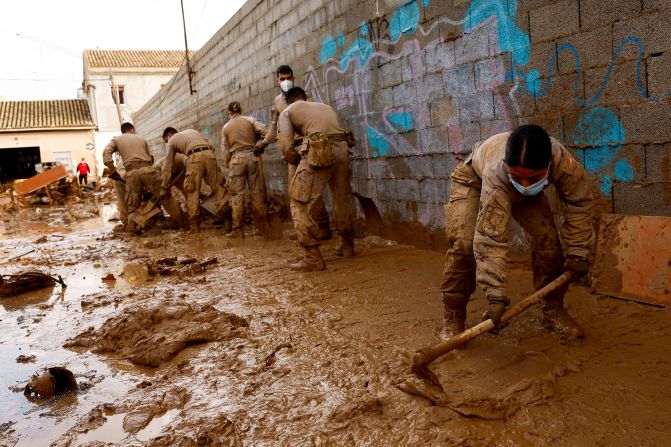 Members of the Spanish military clean a mud-covered street in Massanassa on Sunday.