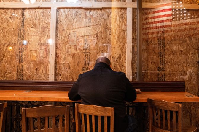 A patron eats inside a restaurant near the White House that had plywood covering its windows on the eve of Election Day.