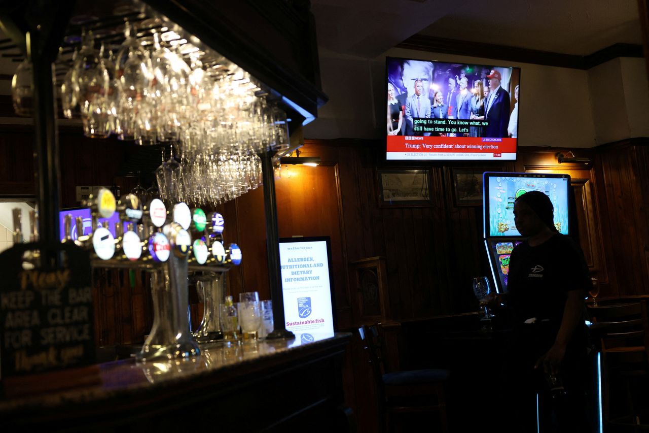 A person walks inside a pub, whilst a television showing the U.S. election in the background, in London, Britain, on November 5.