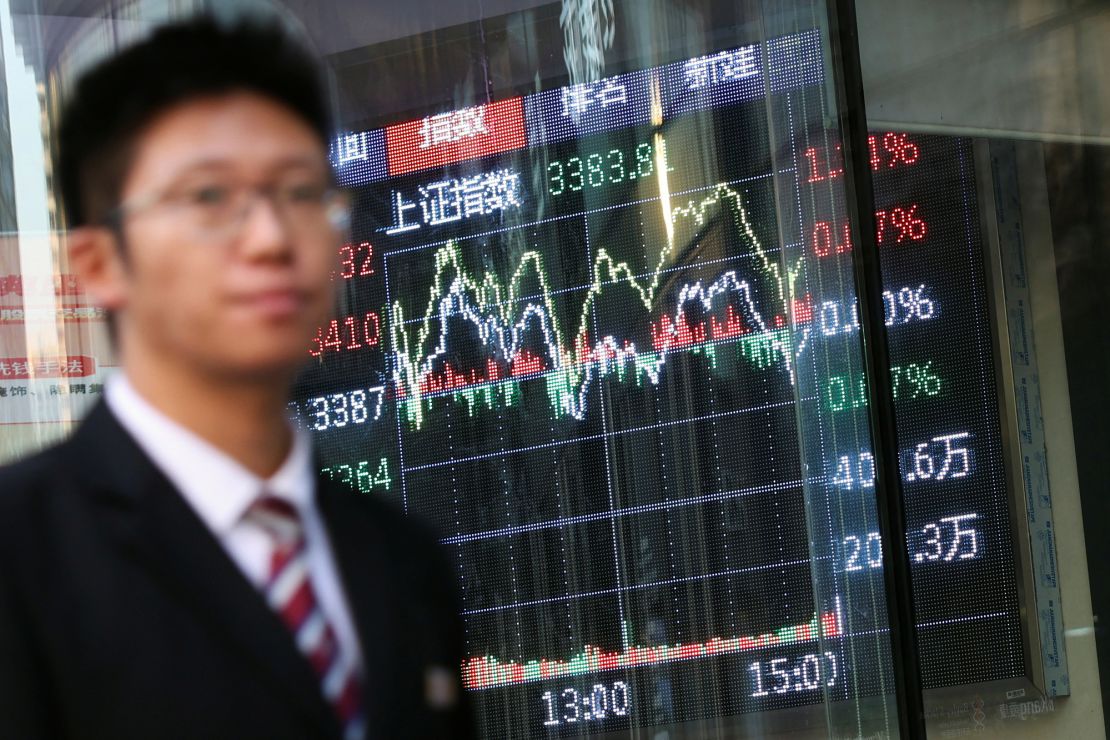 A man walks past a brokerage house with a display board showing the Shanghai Composite Index and other stock information, in Beijing, China, on November 6, 2024.